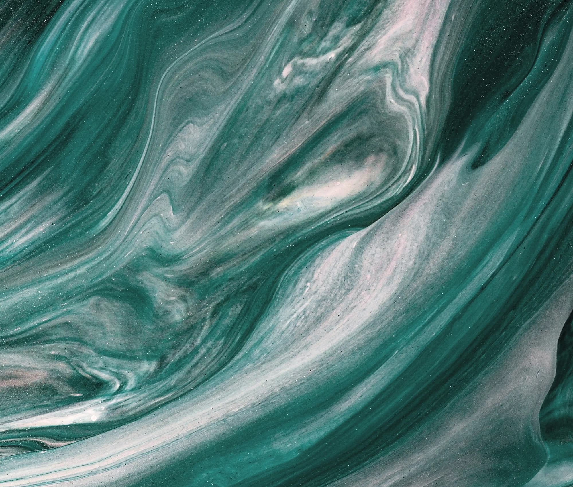 A close-up abstract image of teal and white marbled liquid, swirling together in a smooth, glossy pattern.